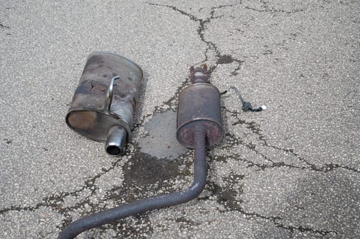 Broken exhaust and muffler of a car, rusted silencer fallen down on the road, breakdown of vehicle