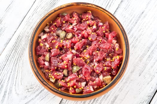 Portion of Beef steak tartare in wooden plate