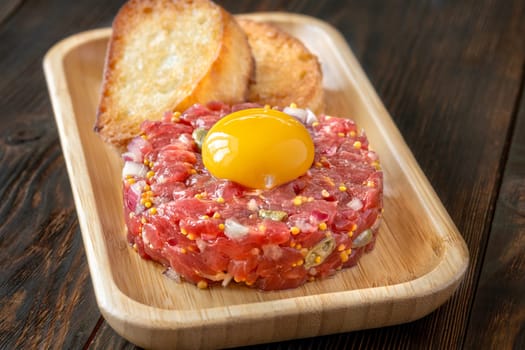 Portion of Beef steak tartare topped with a raw egg yolk