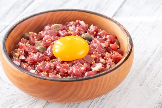 Portion of Beef steak tartare topped with a raw egg yolk