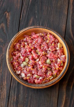 Portion of Beef steak tartare in wooden plate