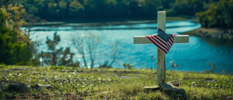 A solitary white cross with an American flag stands by a tranquil lakeside, reflective of sacrifice and patriotism