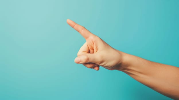 A persons hand is seen pointing at something on a plain blue background. The index finger is extended towards an unseen object, indicating direction or focus.
