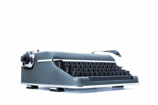 old-style vintage mechanical typewriter made of metal, with black keys and a distinct lever for the carriage return. Set on a white backdrop, viewed at three-quarters from its level