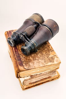 Vintage leather notebooks, ancient notes topped with last century's binoculars depicting adventurers and voyages. Objects isolated on white