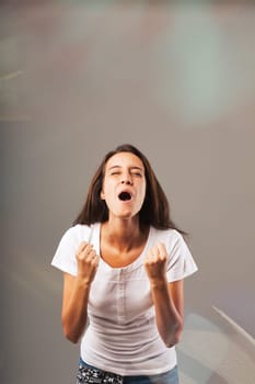 'Yes! Hooray!' Long-haired woman in a white shirt displays exultation and satisfaction for success and victory. Colored lights, glows amplify the positivity
