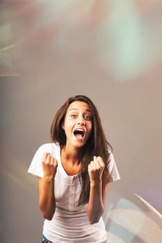 Yes! Hooray! How joyful! Expressions and gestures of exultation and satisfaction for the joy of success and victory displayed by a long-haired woman in a white shirt. Colored lights and glows reinforc