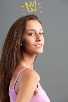 glance over her shoulder in a portrait of a slim young woman in a pink tank top and long hair with an expression of conceit and vanity augmented by a graphic crown on her head - concept of feeling sup