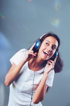 Blue headphones-clad girl dances, sings to music amidst dazzling, fast-paced party lights. Evident joy, happiness, and amusement on the face of slim, long-haired young lady