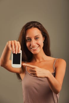 Girl looks our way, excitedly points at empty COPYSPACE on old cellphone screen, happily encouraging use of new technology to reach goals. Cheers to progress!