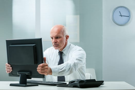stern senior executive grabs his computer screen, hinting at financial problems or unforeseen mistakes. He seeks to swiftly rectify with his signature resolve
