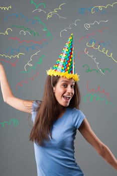 Girl in pointed hat, harlequin colors, and party horn enjoys amidst an explosion of colors and graphic confetti. Festivities, fun, anniversaries, and birthday celebrations