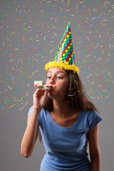 Party girl dons pointed hat, harlequin colors, and horn amidst colorful explosion of graphic confetti. Fun, festivities for anniversaries and birthdays