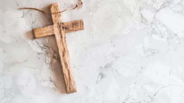 A wooden cross is placed on a sleek marble surface, creating a simple yet striking contrast between materials. The cross stands upright, casting a shadow on the smooth white marble.