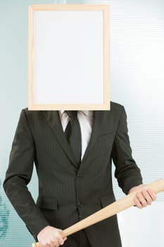 Sign-headed man framed in an office, standing and holding a baseball bat in a threatening manner. He appears to be ready for violent and negative actions. Concept of punishment or threat and aggressiv