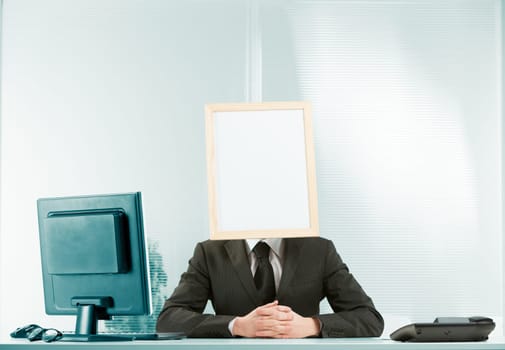 Stasis, bureaucracy, wait-and-see, obstruction and ostracism, conveyed by a man in an office with a sign for a head and a posture with clasped hands that seems to say, 'I am here to obstruct you,' don