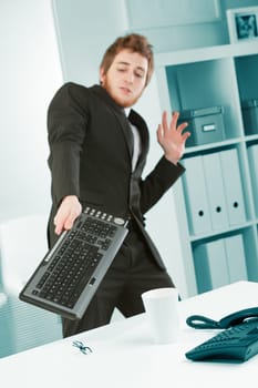 An office worker is terrorized by a bug that he chases away with his keyboard. He is afraid and tries to ward off that spider that scares a young businessman with a wireless computer keyboard.