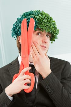 A clerk in black pinstripes in the office nonchalantly trims a 'tuft' of hair-leaf, as if pruning a hedge that stands on his head were surrealistically normal. He performs this action with a very larg
