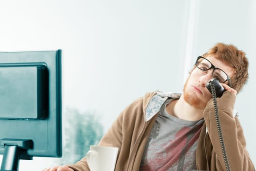 Funny image of young worker exasperated by ongoing telephone conversation. He is eyrolling and as a customer service representative waits patiently, but stresses himself a lot before consulting his co