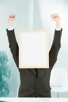 Businessman with sign head and hands raised in jubilation. There is great enthusiasm at the workplace for the light-wood framed COPYSPACE.