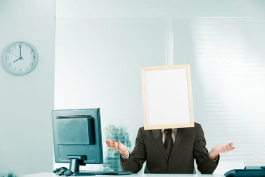 Helplessness, no help, stasis, bureaucracy, wait-and-see, obstruction and uselessness, conveyed by a man in an office with a sign for a head and a posture with his hands open palm up that intends to s