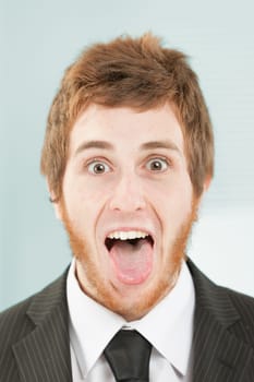 Close-up frontal portrait of young man with short red hair and beard. Crazy expression with eyes and mouth wide open, tongue out, smiling person.
