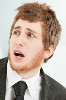 Close-up portrait of young man with short red hair and beard. Frightened expression as he looks to his own left above. Almost terrified of what is coming.