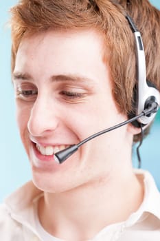 Young call center employee with red hair. Behind him, productivity charts blur, judging his work
