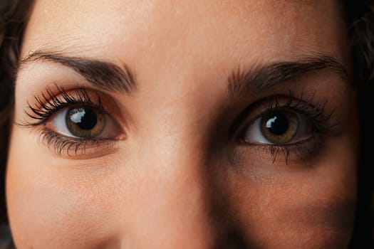 Extreme close-up captures a woman's eyes. One eye mirrors a universe: stars or light-absorbing black holes. Intriguingly, it feels luminous, beckoning like a beacon. It's the soul's reflection and a t