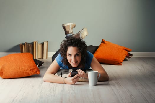 Nestled amidst home cushions, a young curly woman navigates the vast cyber realm with her phone. Engaging in everything from social interactions to gaming, watching adult content to streaming shows, s