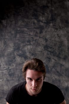 Standing before a vertical chalkboard, a sly young man plots. His expression speaks of joy in duping others. Plenty of copyspace for your malicious content