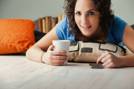 Amidst house cushions, a curly dame relaxes, diving into her phone's rich landscape. Whether it's socials, streaming series, video games, or viewing adult content, she indulges from her home's snug at