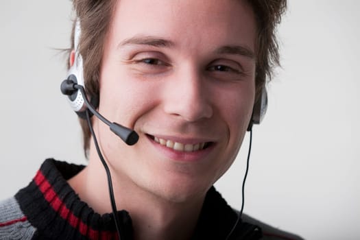 friendly young call center man answers clients' calls with a smile, embodying the company's promise of excellent customer service. Wearing a black and gray sweater and a professional headset