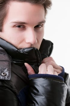 With a dark, charismatic stare, a young man adjusts the collar of his black down jacket, hiding everything but his eyes. It's a mix of winter trend and masculine charm