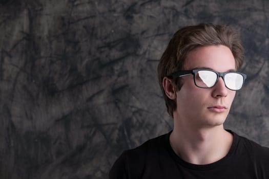 Mysterious reflections in his glasses, a light-brown-haired man stands against grunge. In a black shirt, he's absorbed in concerns for humanity's future amid tech discoveries