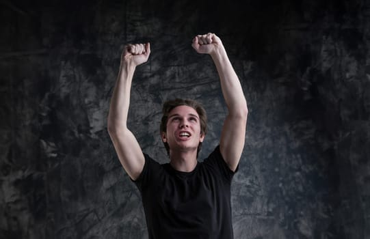 Victory is clear on a young man's smiling face. Light-brown hair, black shirt, with arms uplifted, he symbolizes success against grunge
