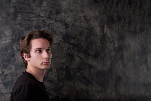 In a black t-shirt, a man stands pondering in front of a wiped chalkboard, signifying an upcoming brilliant idea. Ample copyspace for your input