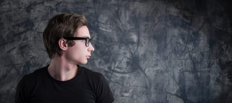 Pondering deeply, a young man with light-brown hair contrasts a grunge backdrop. His intense look creates a perfect COPYSPACE