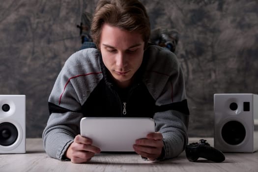 On the floor, a man with a tablet and gaming setup. With endless online content, there's no need for DVDs, CDs, or books anymore
