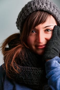 spirited young woman loves her winter fashion. Dressed in wool gloves, hat, scarf, and snug sweaters, she's warm despite the chill. Her long brown hair and bright eyes are captivating