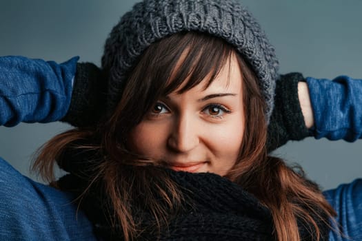Regardless of the chill, a woman with long brown hair and vibrant eyes enjoys her winter outfits: wool gloves, scarf, and cozy jumpers