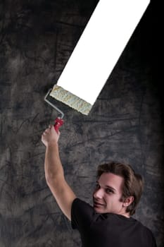 Against a grunge-filled black backdrop, a fine-looking male with a black shirt and light-brown hair strategically rolls a white segment, paving way for COPYSPACE