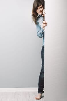 curious young woman in a denim shirt, with long hair, peers from behind a blue-toned COPYSPACE, inviting you to join her interest