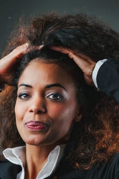 black woman in her 40s, with beautiful curls, exudes confidence in black and white attire. Her success story, against odds tied to race and gender, is an inspiration for countless others