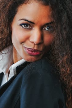 The dance of emotions is evident in the passionate gaze of a beautiful black woman with curly long hair. Her attire might be formal, but her lively spirit shines through