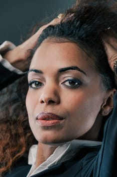In a black jacket and white shirt, a 40-year-old black woman with flowing curls stands out. Despite societal hurdles tied to race and gender, she's emerged stronger, setting a benchmark for many