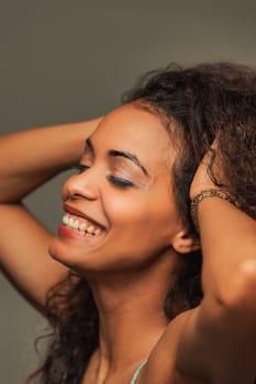 Dancing gracefully, a brown-skinned woman luxuriates in her body's sensations. The sun, nature, and music elevate her spirit, and her captivating beauty is truly infectious