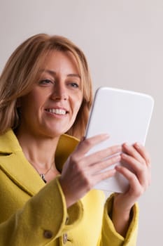 Woman in yellow navigates the vast digital ecosystem via her tablet. Seamlessly moving between professional duties, health, personal tasks, revelry, and the world of online dating
