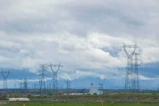 Rural landscape hidden by electric towers, high voltage cables and wind turbines. Wind turbines environmental impact concept