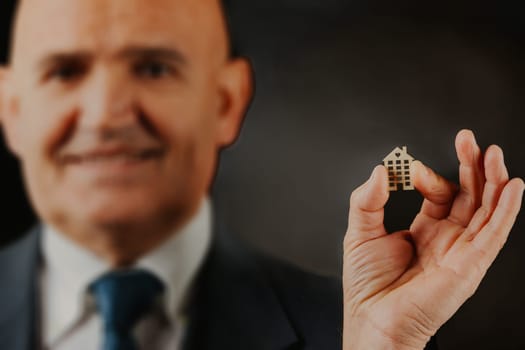 bald older gentleman, smiling radiantly, pinches a miniature representative home, spotlighting the inherent aspiration to buy, ensure its financial safety, and continually ameliorate existence